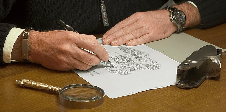 Gravador desenhando o motivo de uma báscula, com lupa